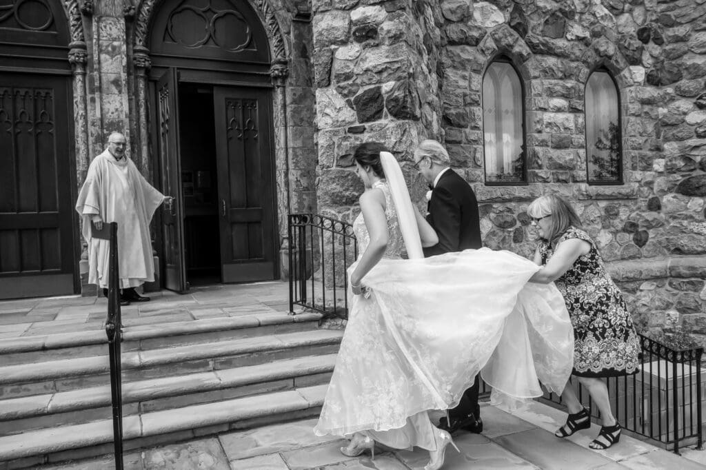 Bride being helped by family as she enters the church before the wedding ceremony