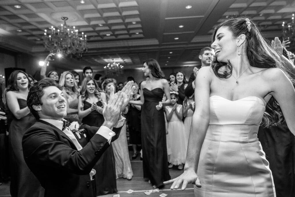Bride laughing during an unposed wedding reception moment surrounded by guests.