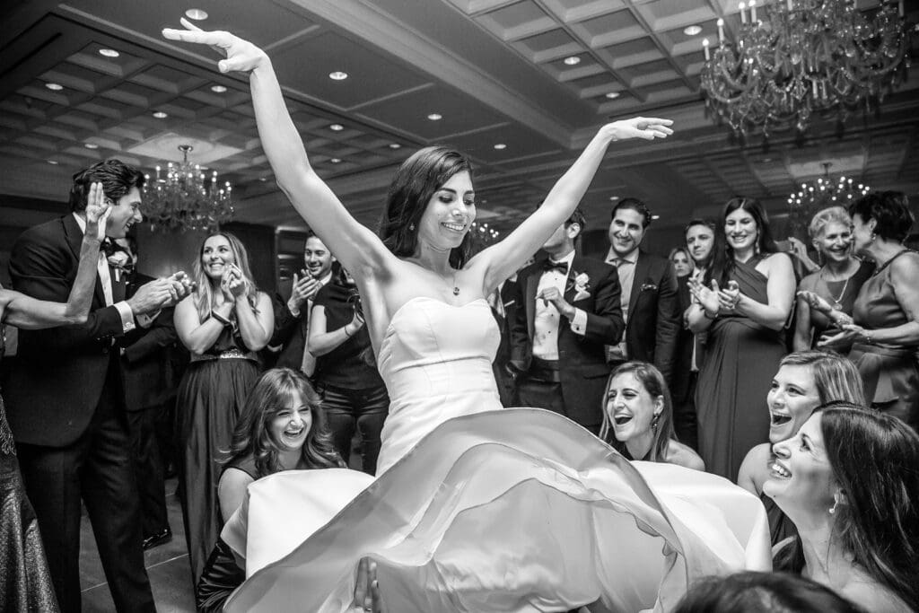 Bride being lifted by friends during wedding reception.