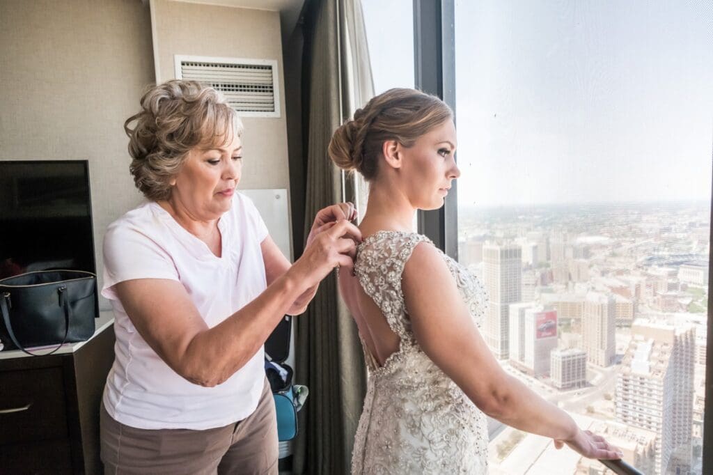 Bride having her dress fastened during quiet wedding morning moments