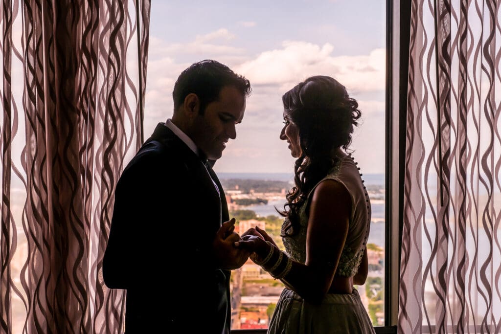 Bride and groom share a quiet, unposed moment by a window, holding hands and connecting privately before their wedding ceremony, photographed in a documentary wedding style.