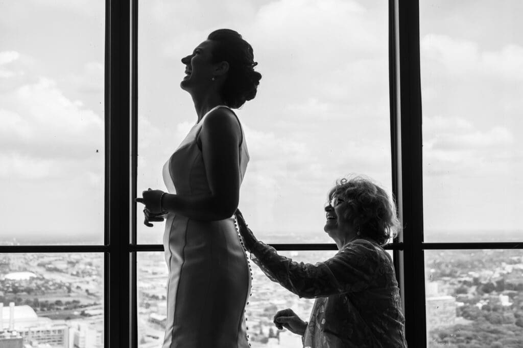 Quiet wedding morning moment as a bride is helped into her dress by a loved one