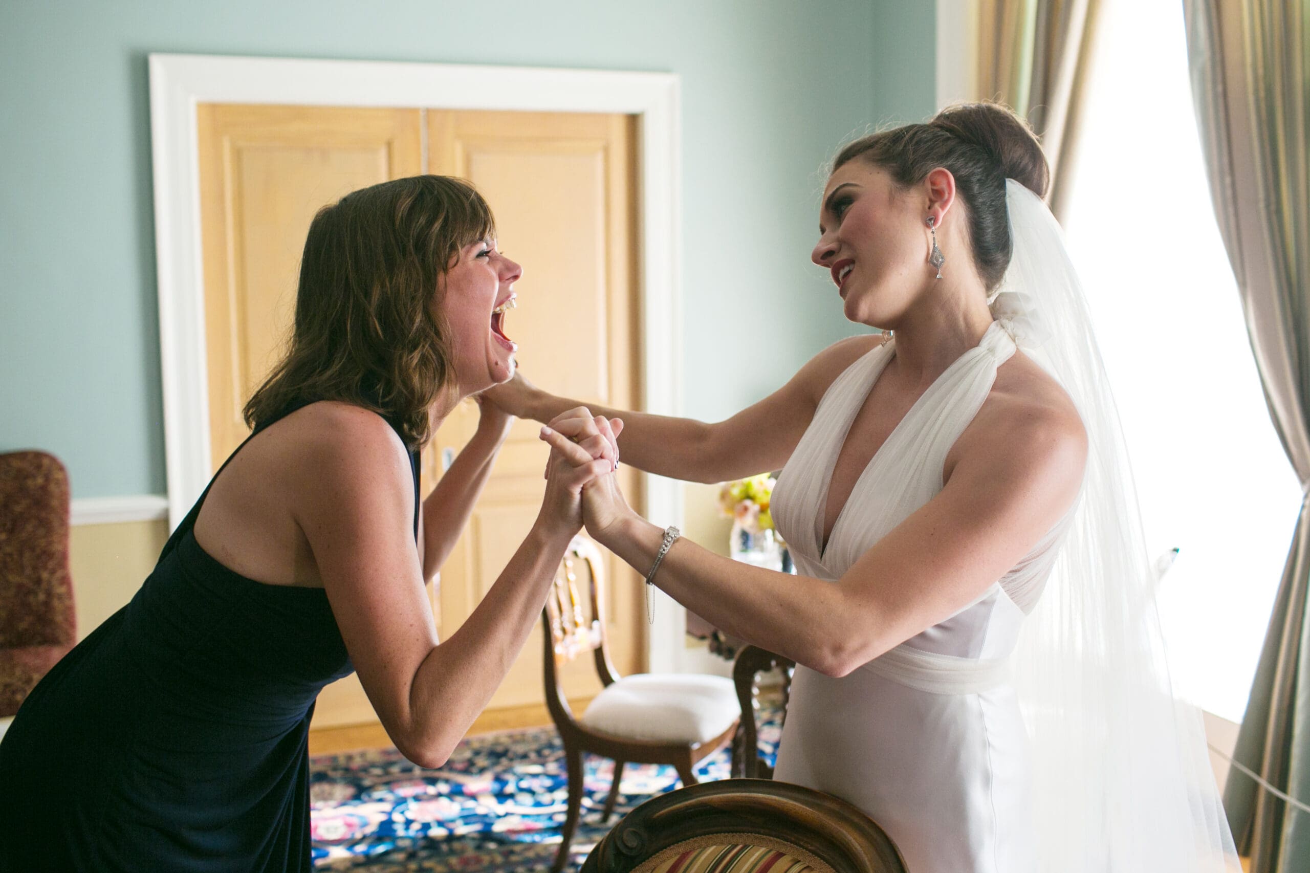 Bride laughing with friend during wedding prep.