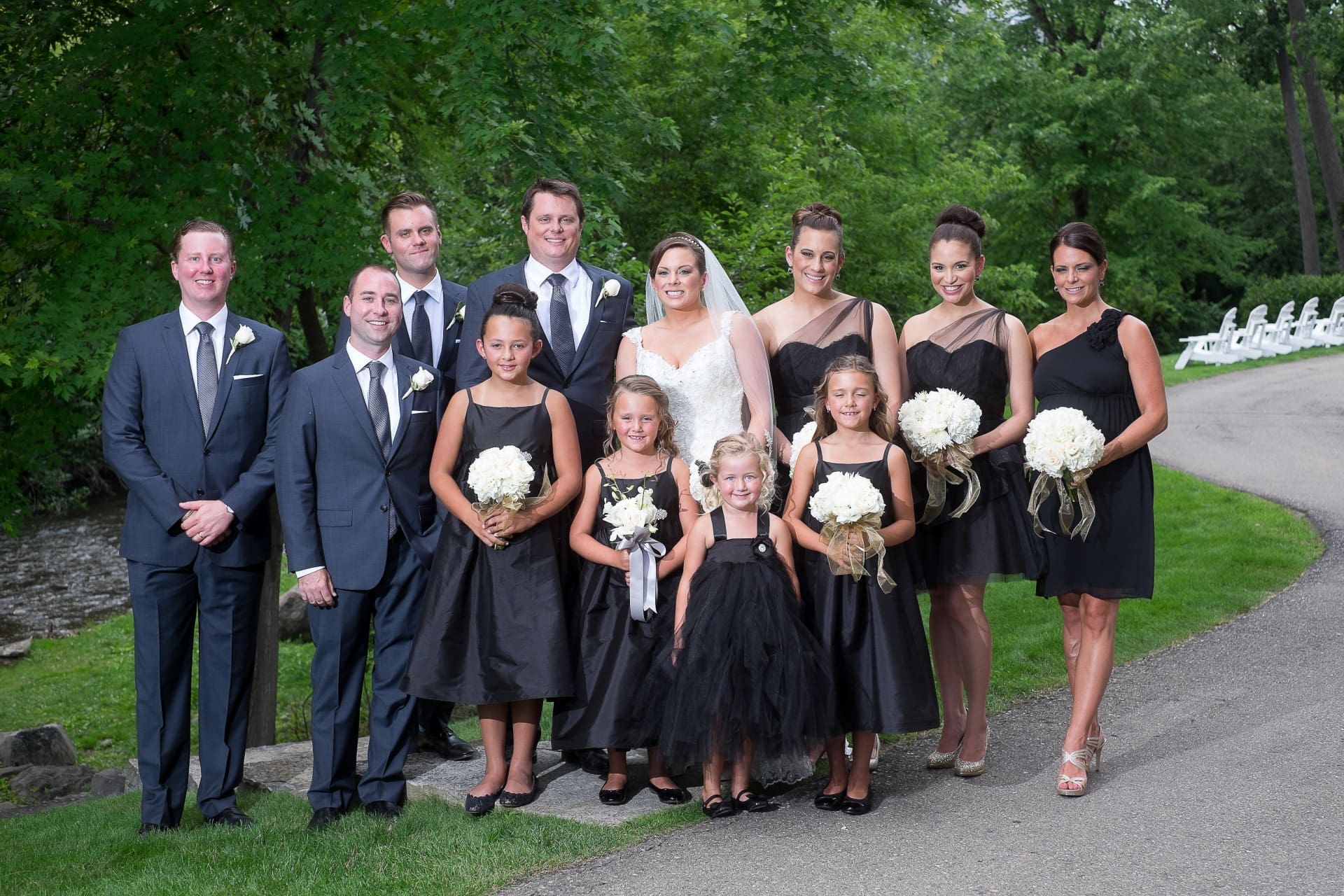 Bride and groom posing with their wedding party during outdoor portraits.
