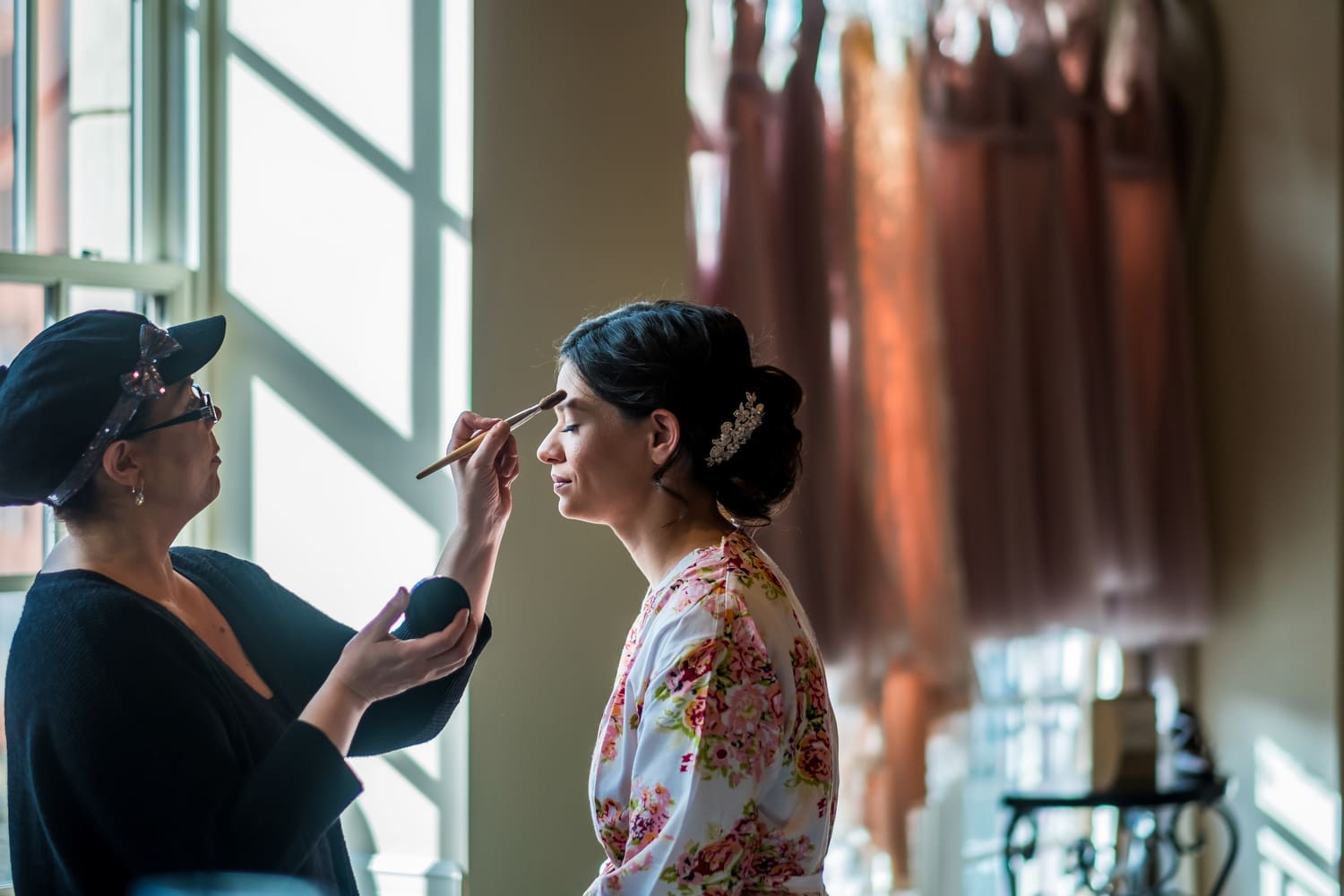 Bride having makeup applied during wedding morning preparations.