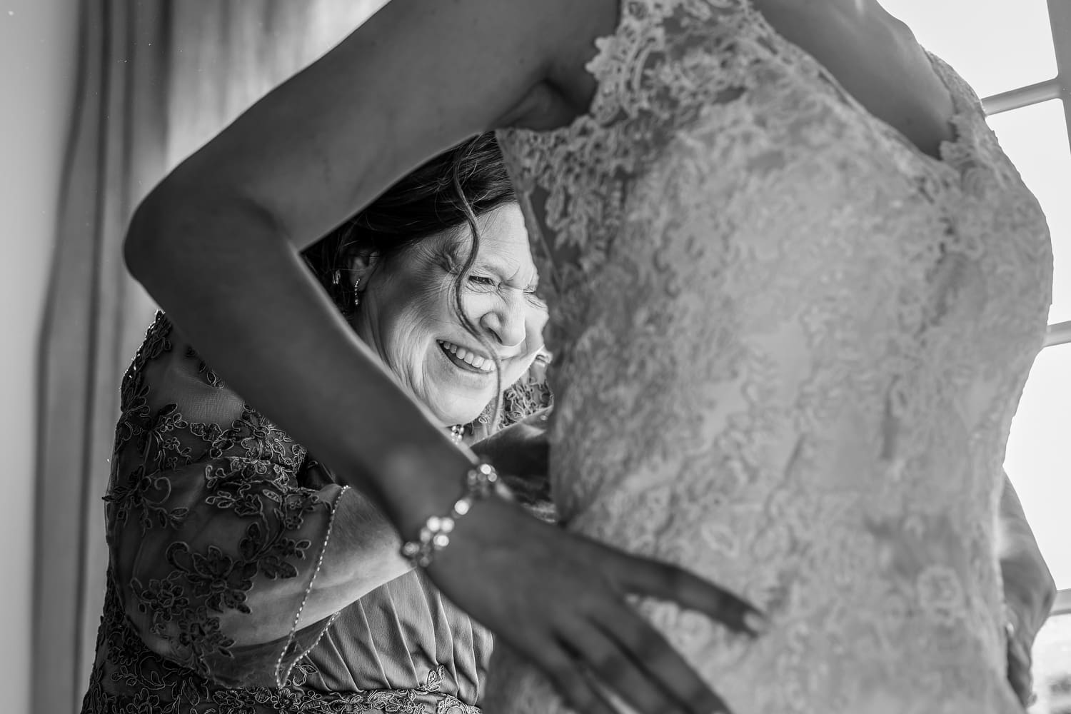 Bride getting into her wedding dress during morning preparations.