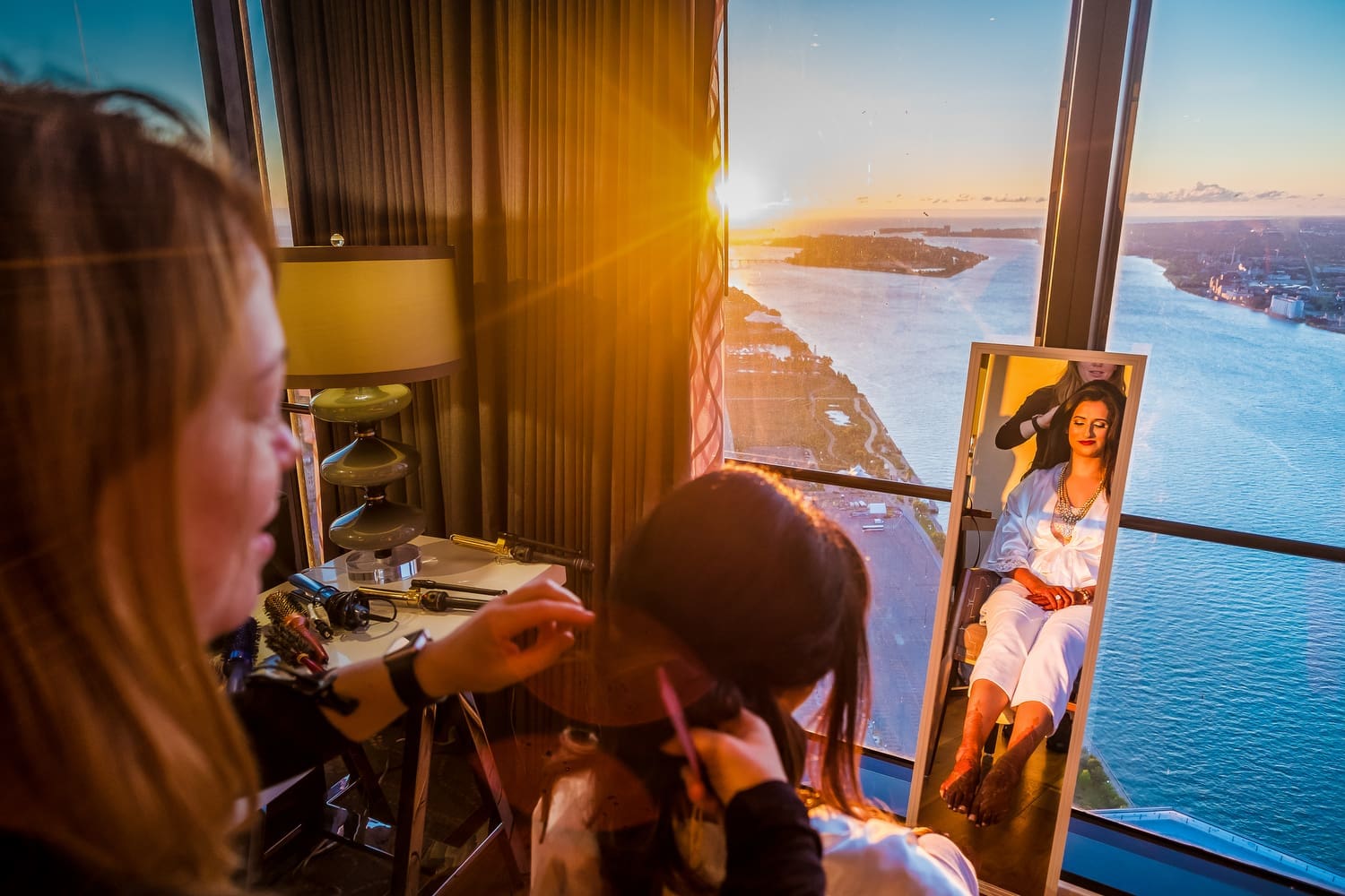 Bride getting ready while having her makeup applied before a Michigan wedding ceremony.