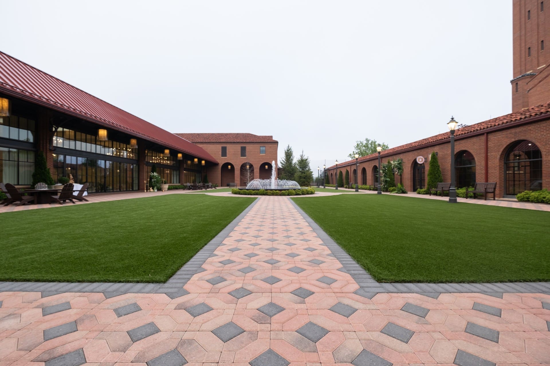 Brick courtyard and fountain at Saint John's Resort featuring landscaped lawns, elegant walkways, and historic architecture in Plymouth, Michigan.