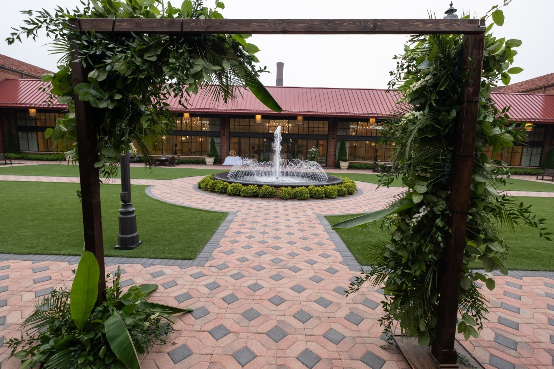 Decorated outdoor ceremony arch overlooking the fountain courtyard at Saint John's Resort, featuring lush greenery, brick walkways, and elegant wedding details.