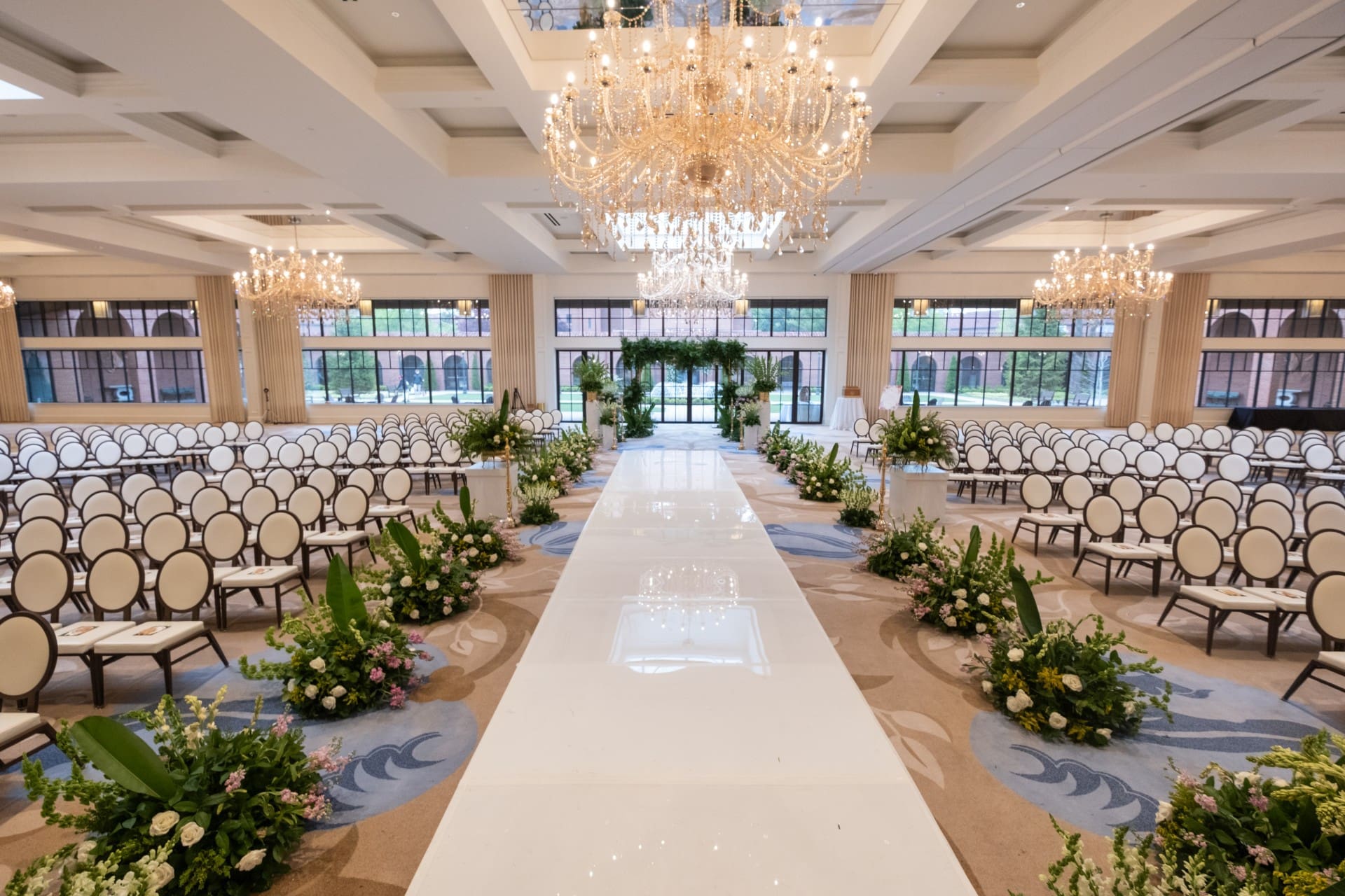 Grand wedding aisle inside Monarch Ballroom at Saint John's Resort featuring crystal chandeliers, elegant ceremony seating, floral arrangements, and a luxury indoor wedding design.