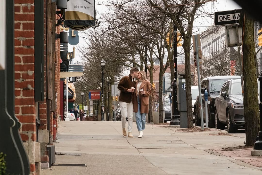 Couple walking through downtown Detroit in coordinated outfits during an engagement photo session.