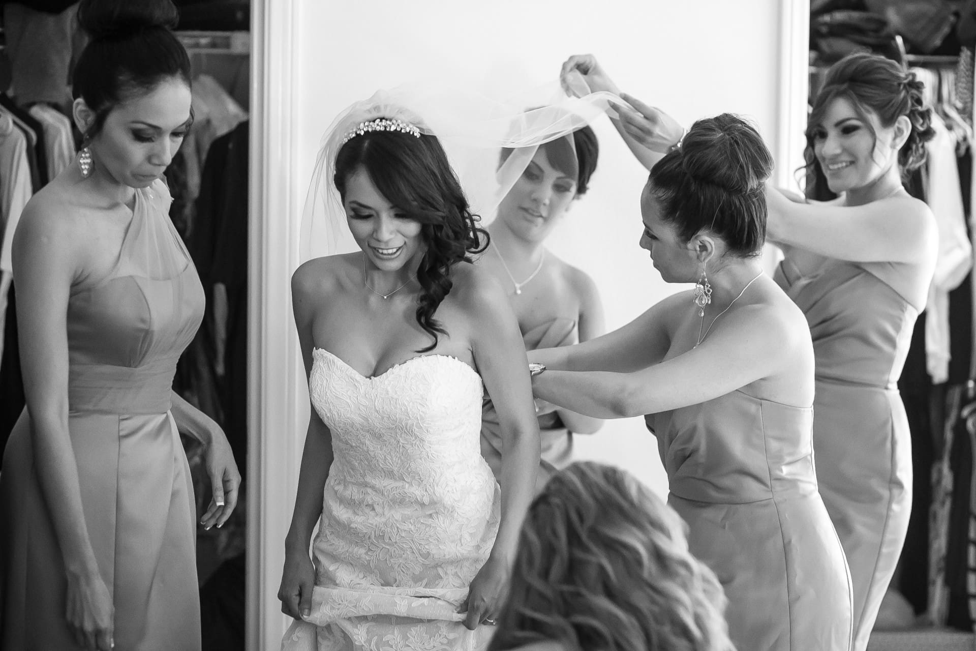 Bride getting into her wedding dress with help from her bridesmaids before the ceremony.