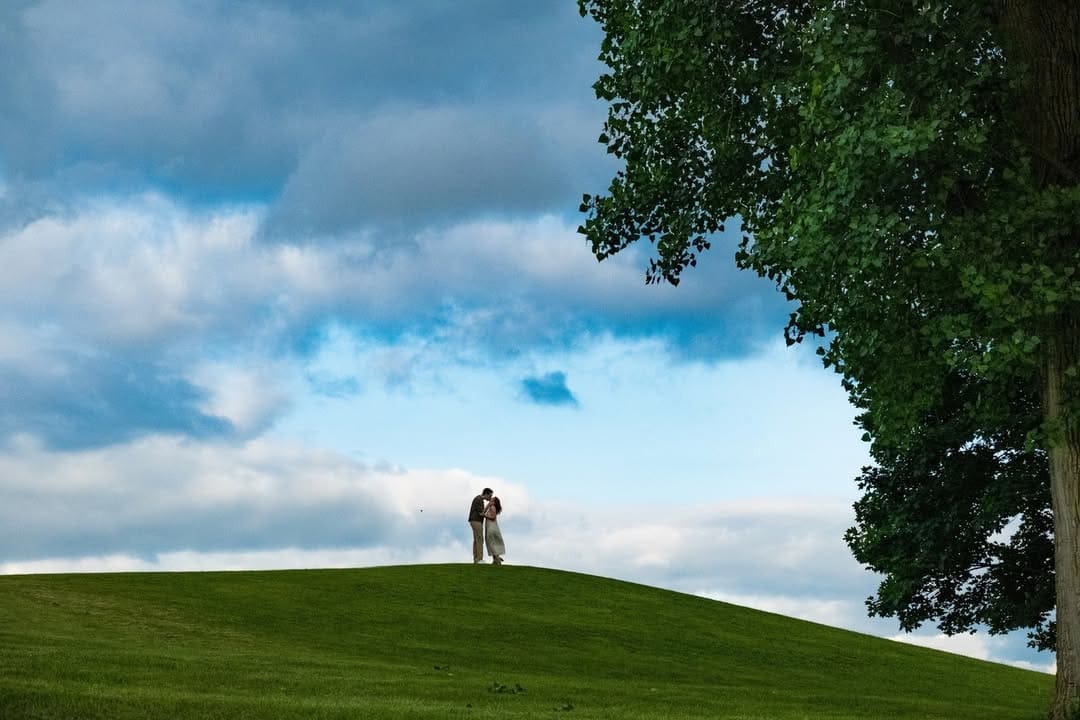 Couple embracing on a scenic hillside during an outdoor engagement photo session.
