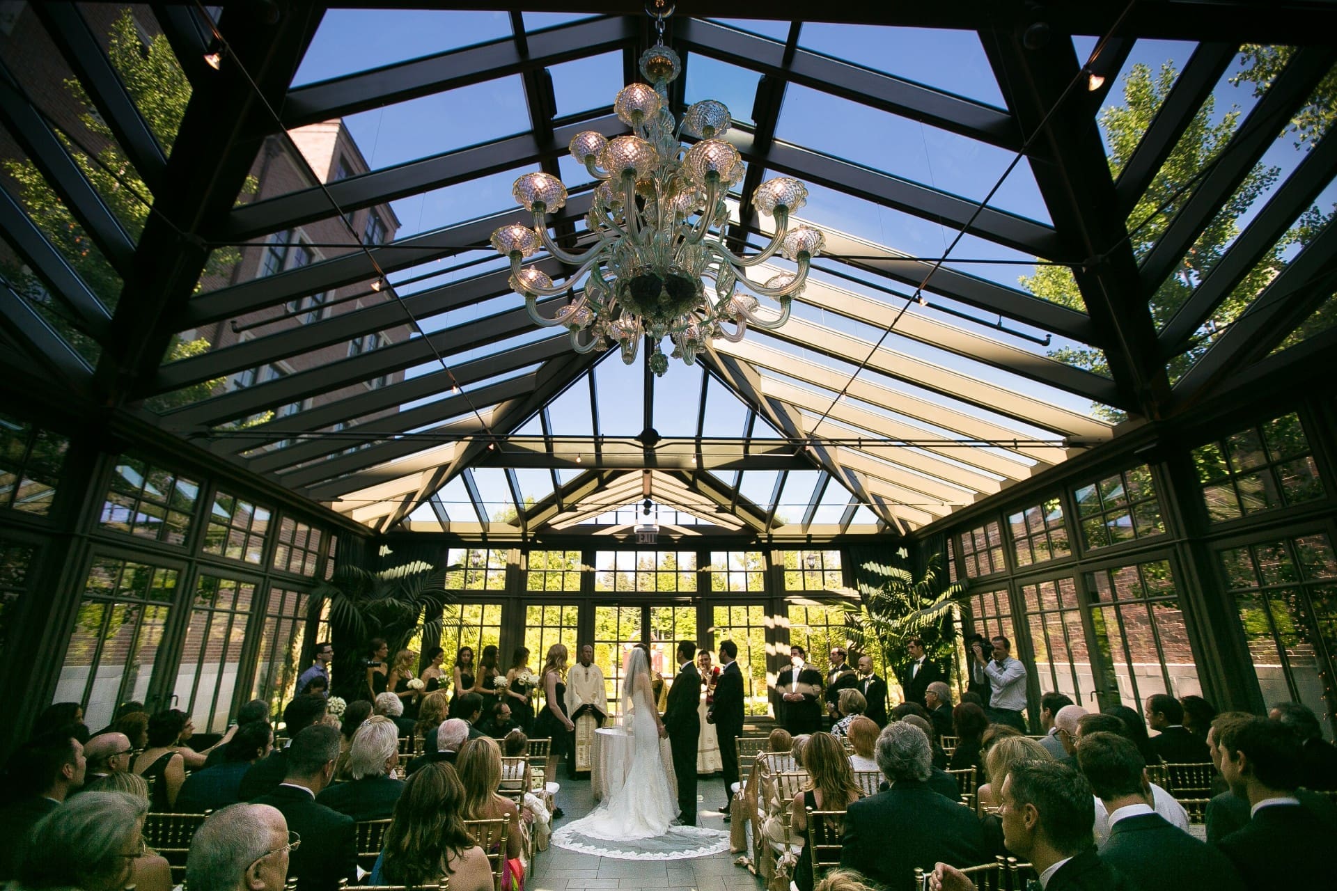 Elegant wedding ceremony setup featuring floral arrangements and a glass conservatory venue.