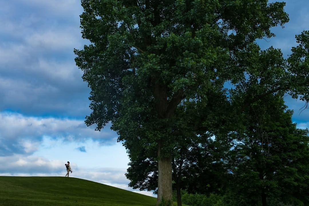 Couple walking across a scenic hillside during an outdoor engagement photo session.