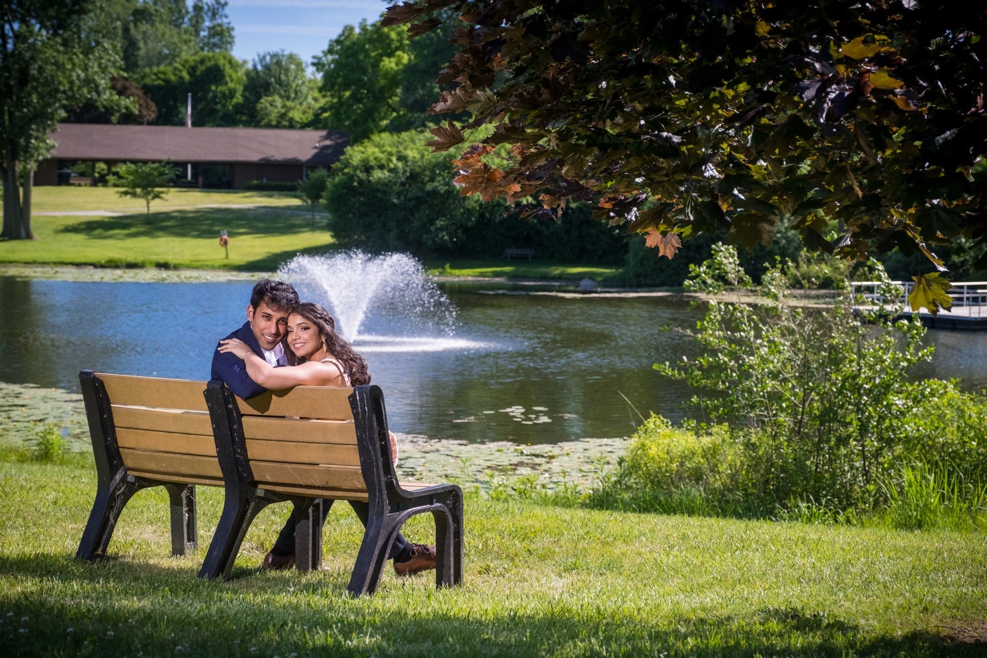 Couple sharing a quiet embrace on a park bench beside the water in Detroit.