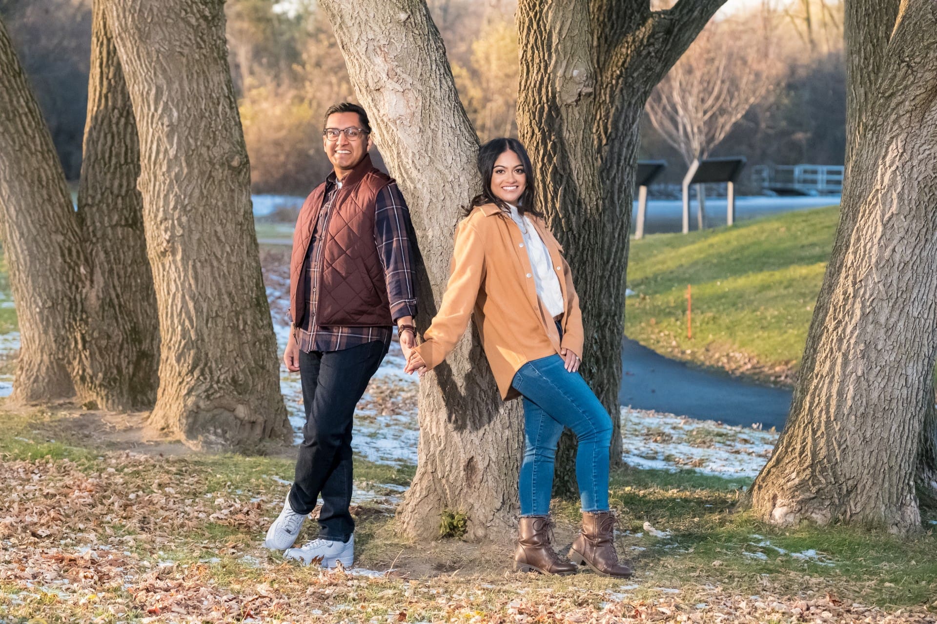 Couple holding hands while walking through a park during an engagement session.