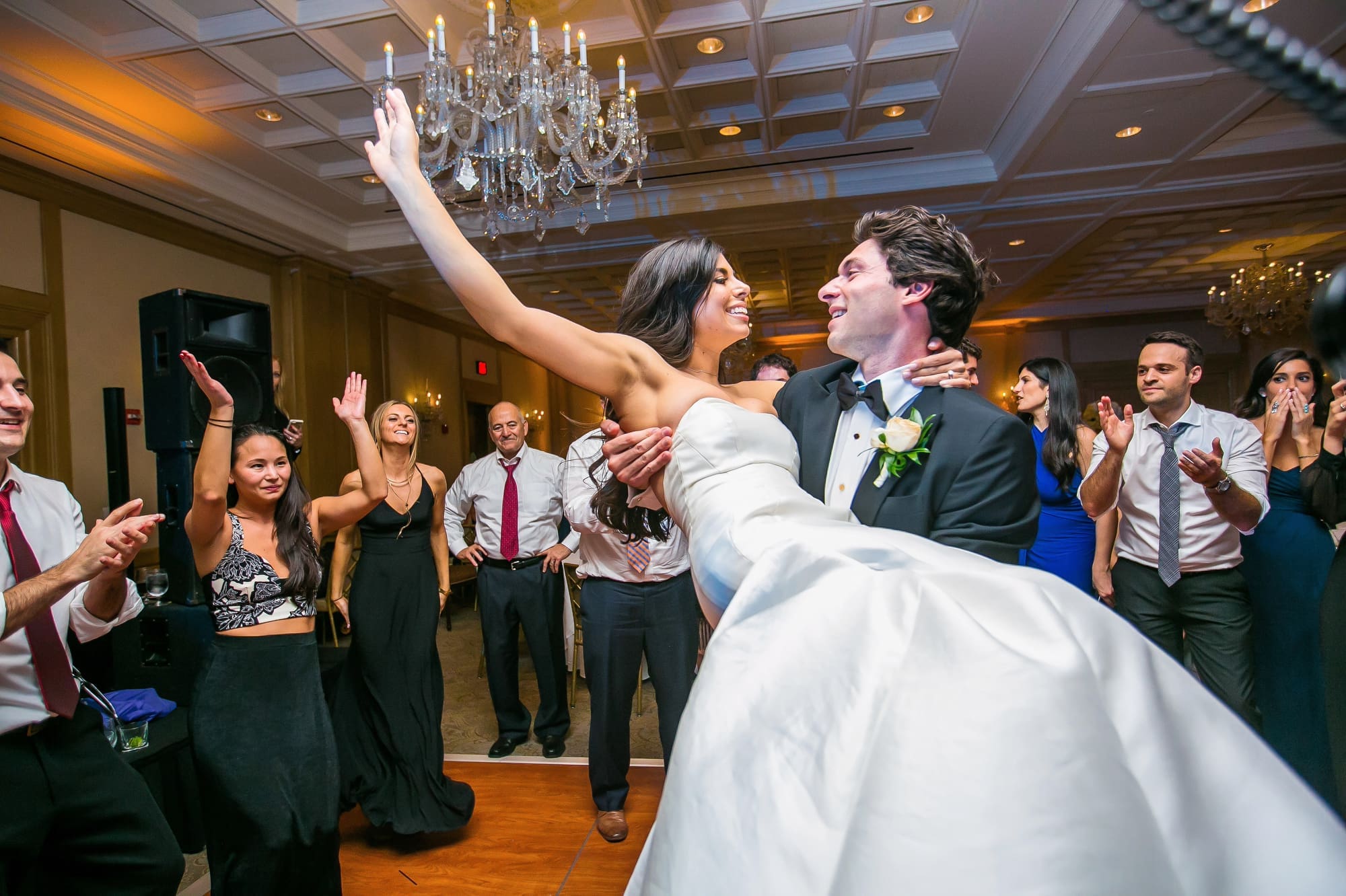 Bride and groom dancing together with wedding guests celebrating during a lively Michigan wedding reception