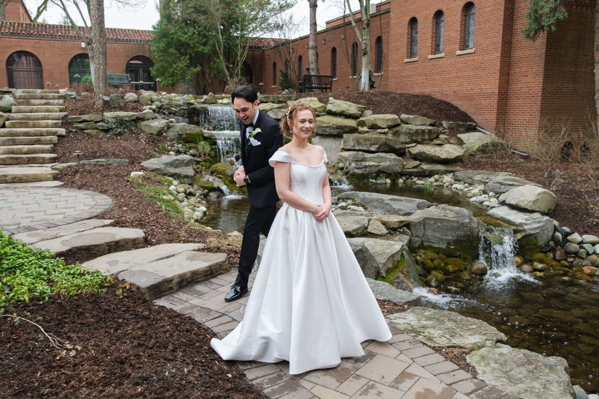 Bride and groom posing together beside a garden stream at a Michigan wedding venue