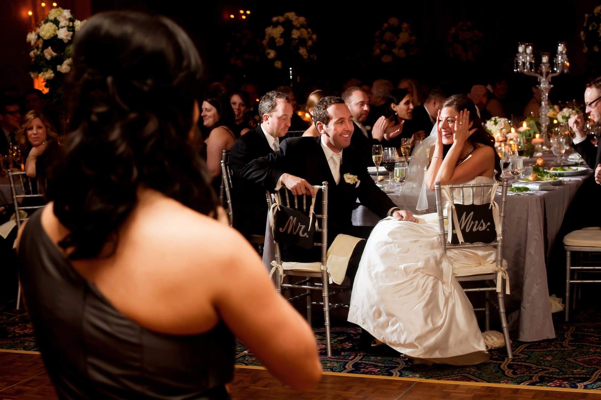 Wedding guests seated at reception tables while celebrating the couple