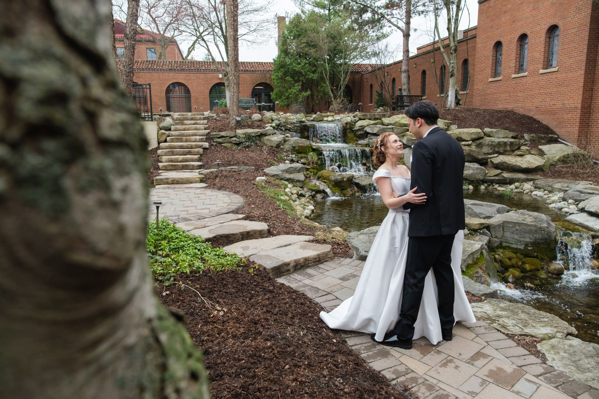 Bride and groom standing together beside a garden stream