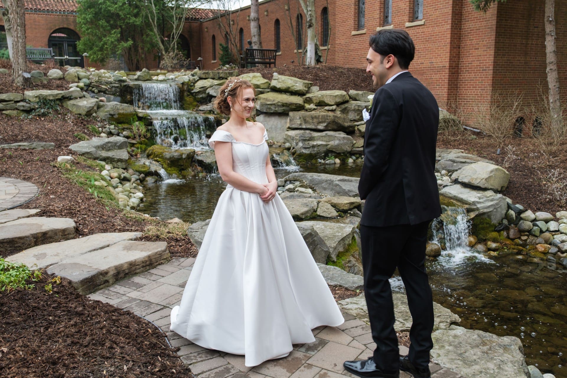 Bride and groom sharing a first look beside a garden stream at a Michigan wedding venue