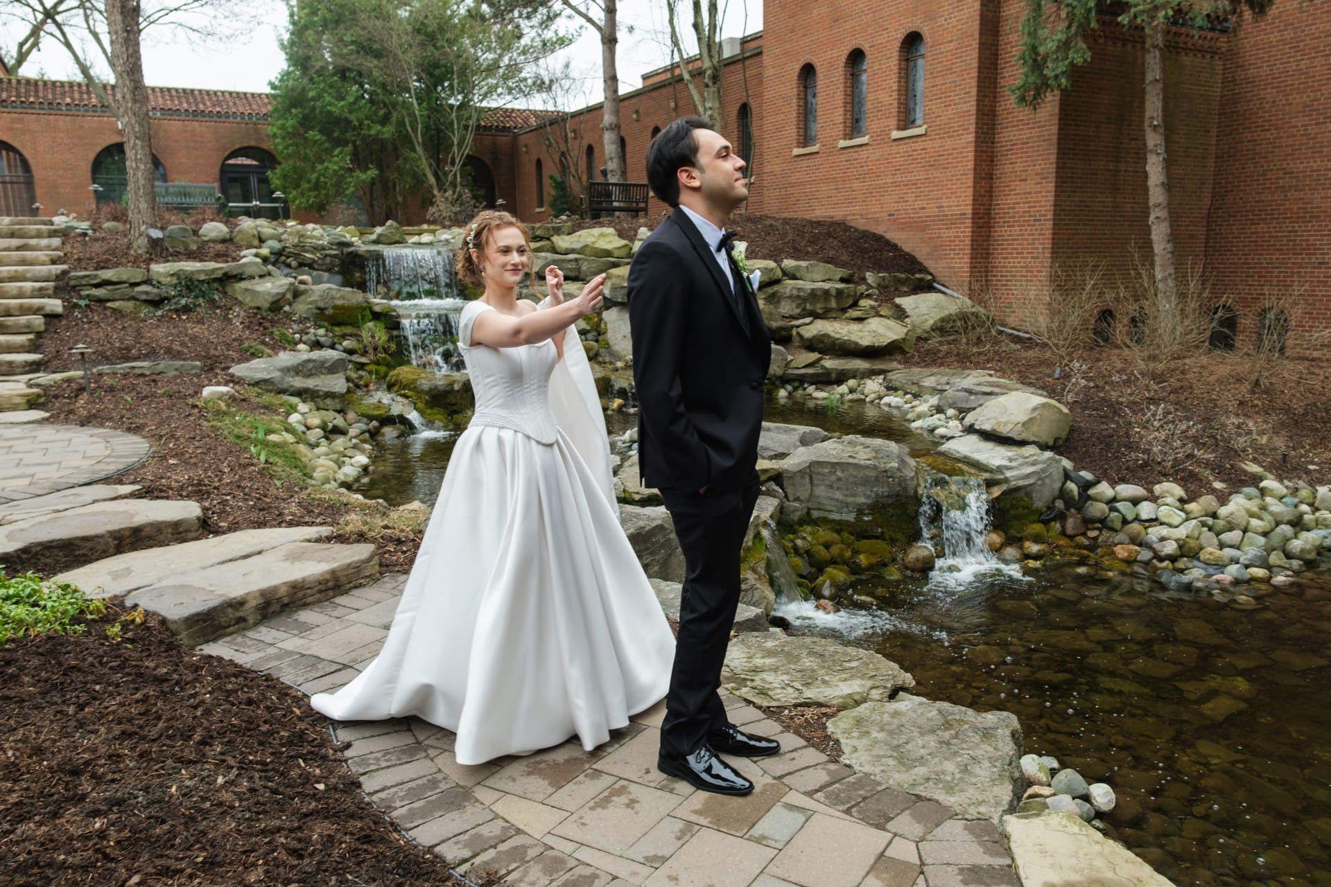 Bride and groom walking together beside a garden stream