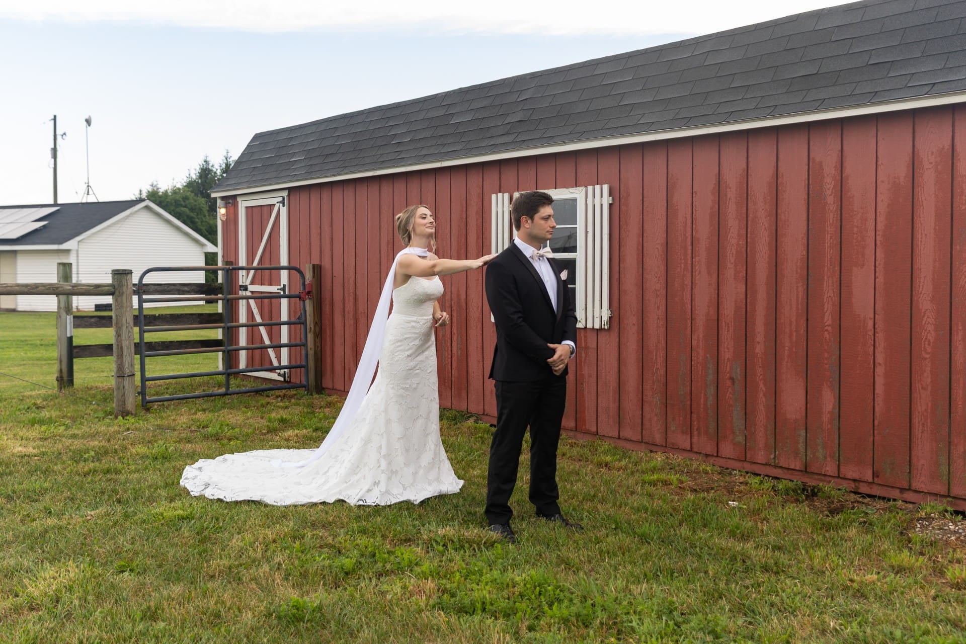 Bride and groom posing beside a rustic red barn in Michigan