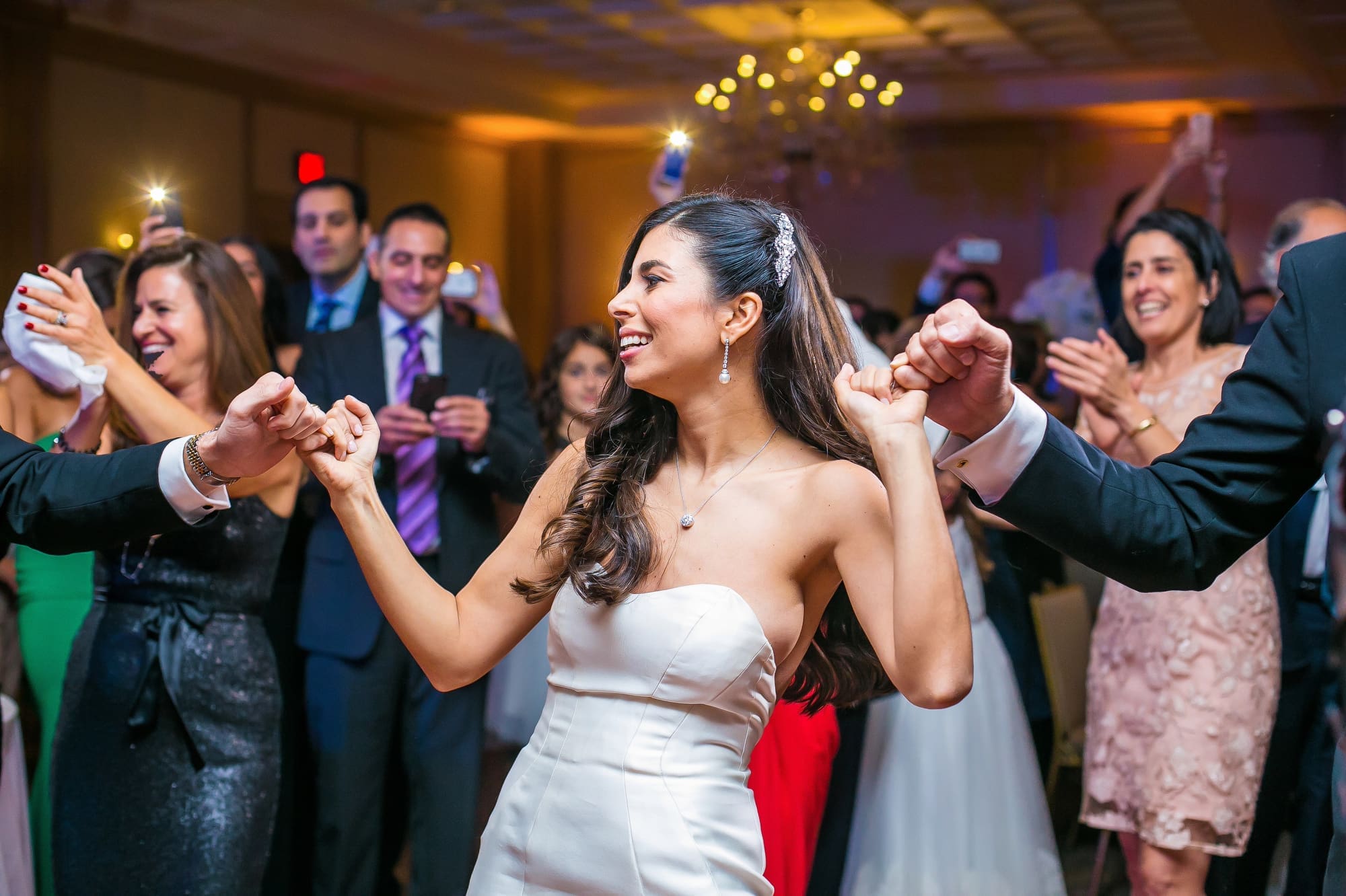 Bride dancing with wedding guests during a lively Michigan wedding reception captured through documentary wedding photography