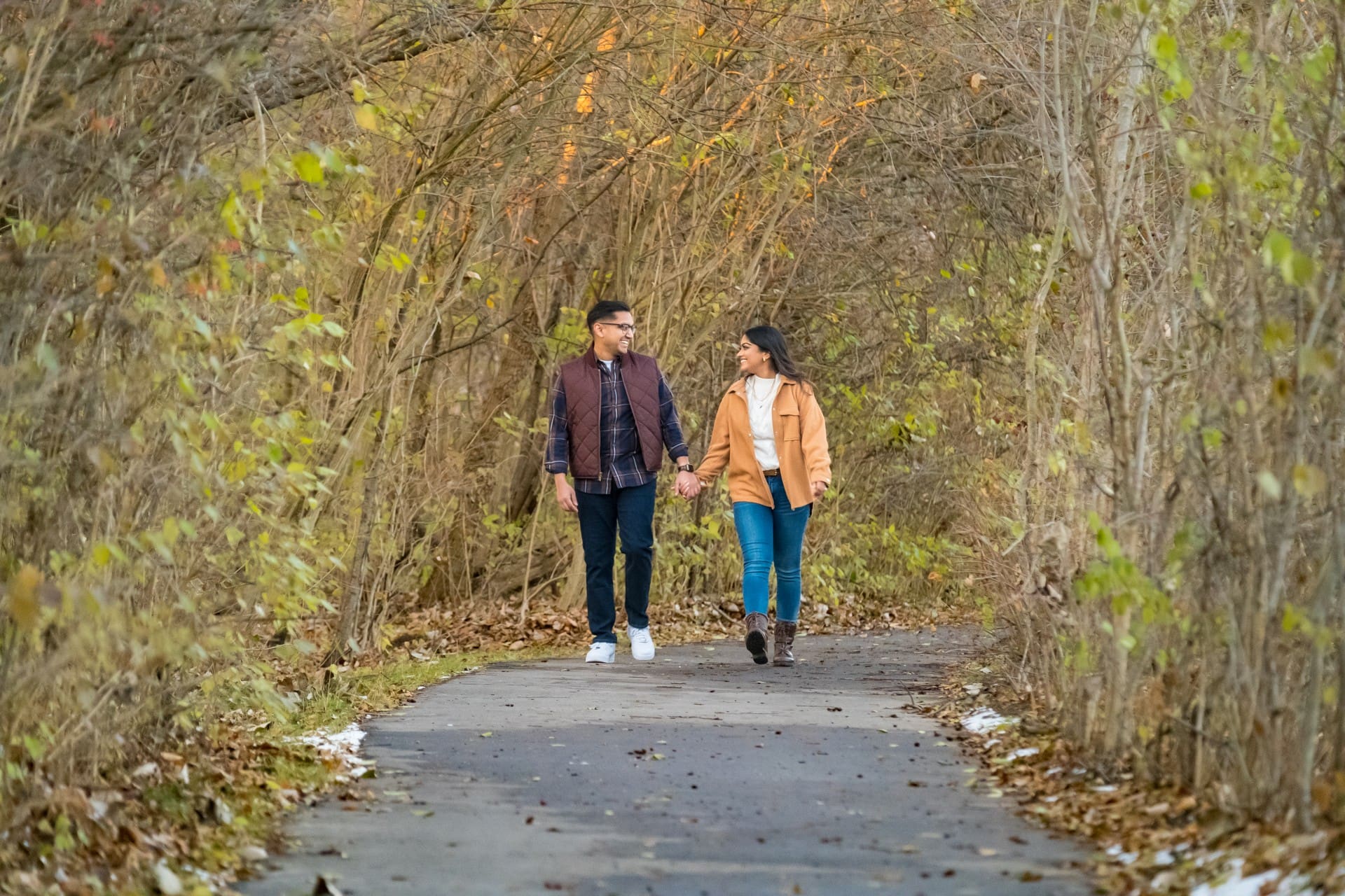 Couple walking hand in hand along a wooded path