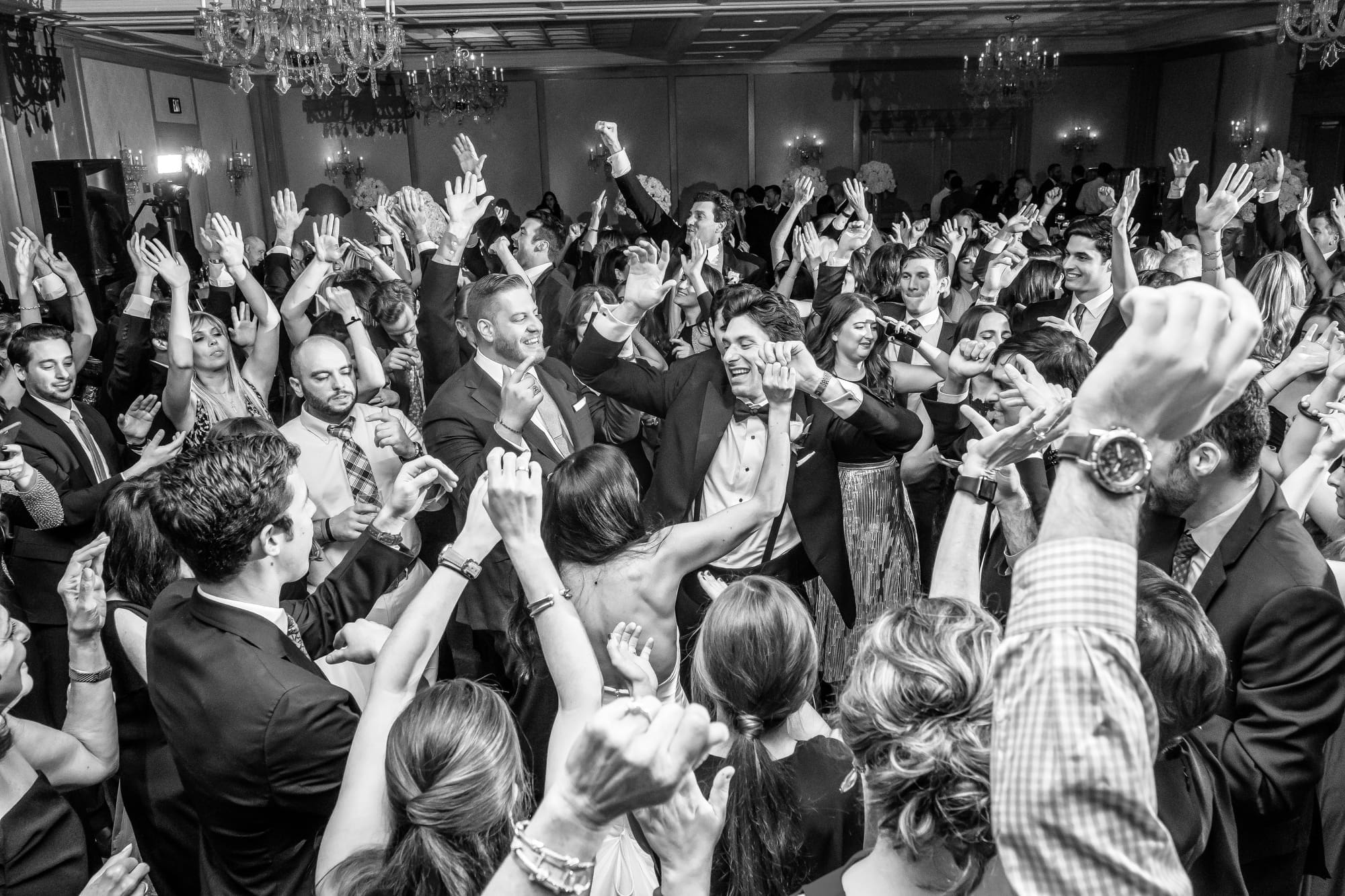 Wedding guests dancing and celebrating together with their hands raised during the reception
