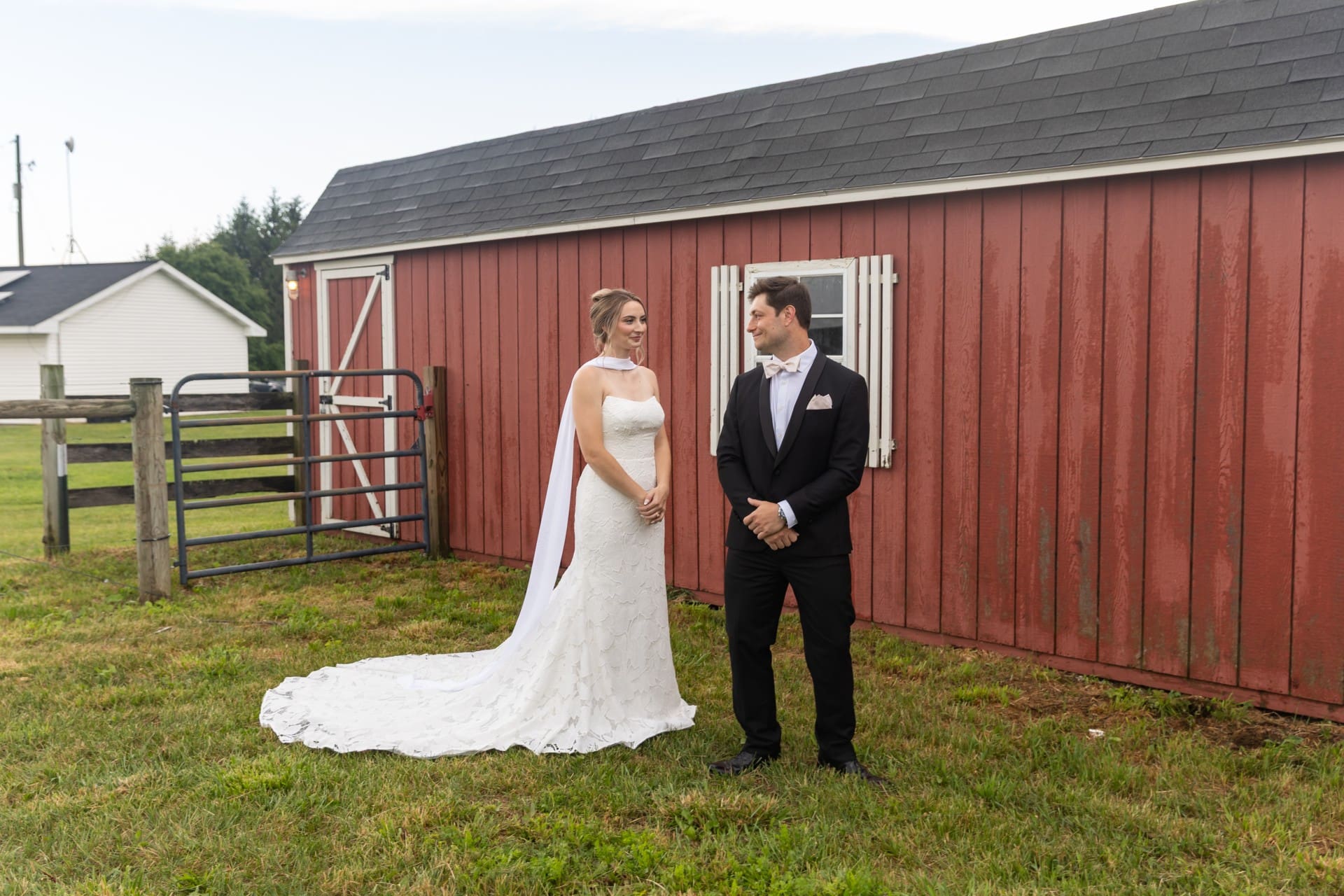 Bride and groom standing together outdoors near a rustic barn