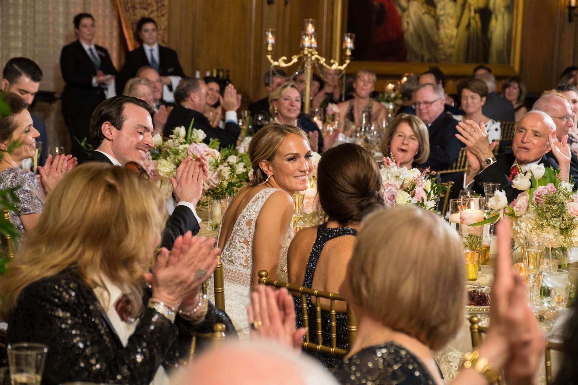 Bride looking back and smiling as wedding guests applaud during the reception