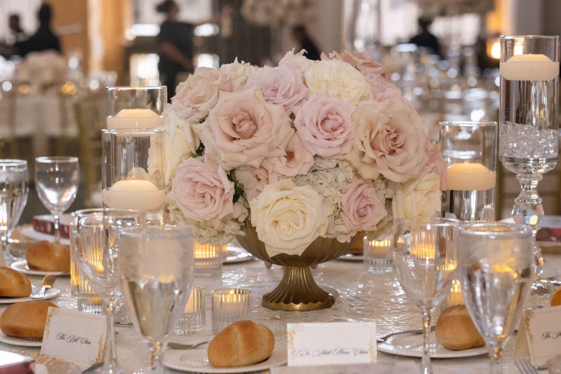 Elegant blush and ivory floral centerpiece with candles and table settings at the Chang 50th Anniversary