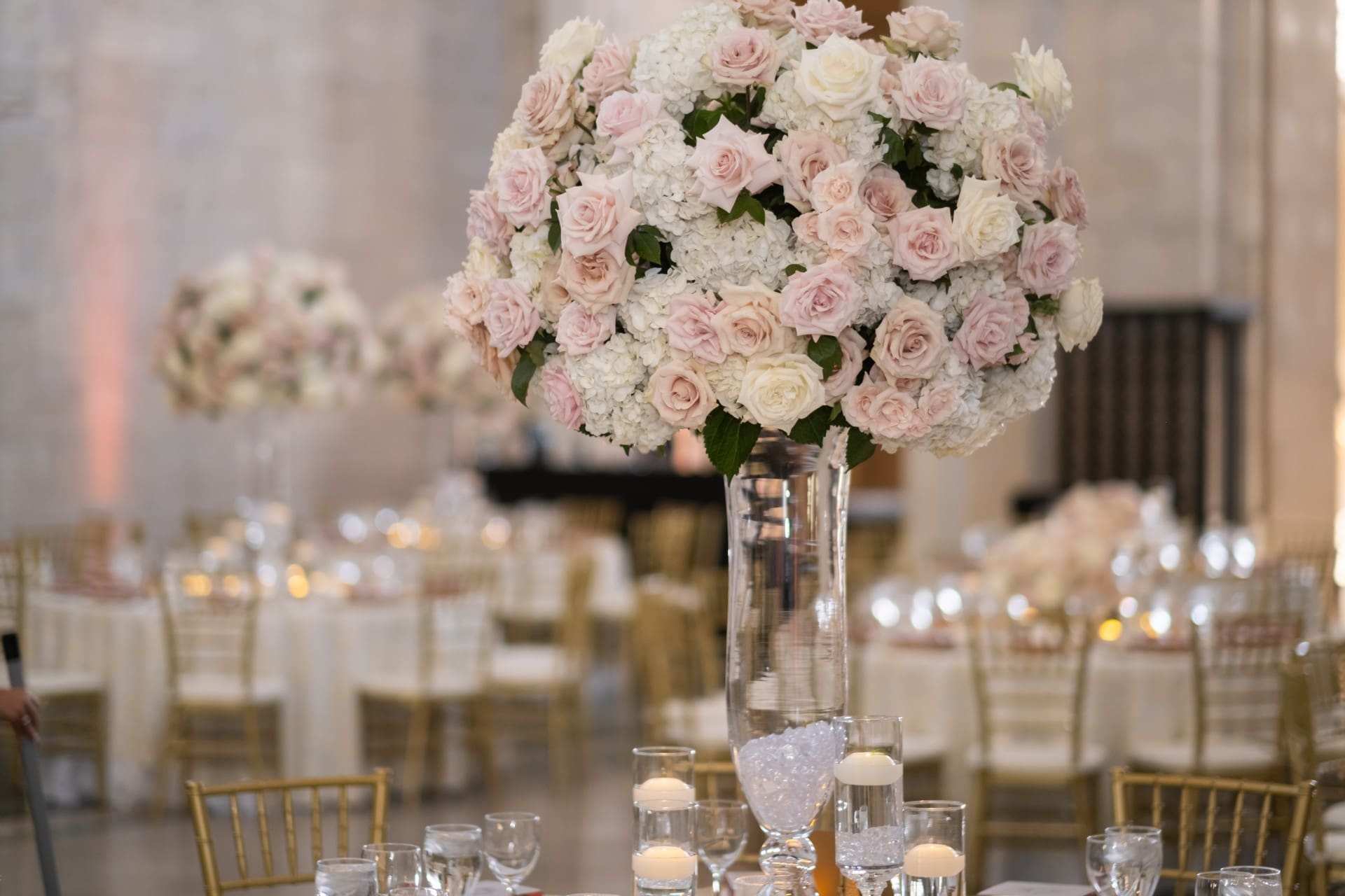 Blush and ivory floral centerpiece with candles and elegant table settings at the Chang 50th Anniversary