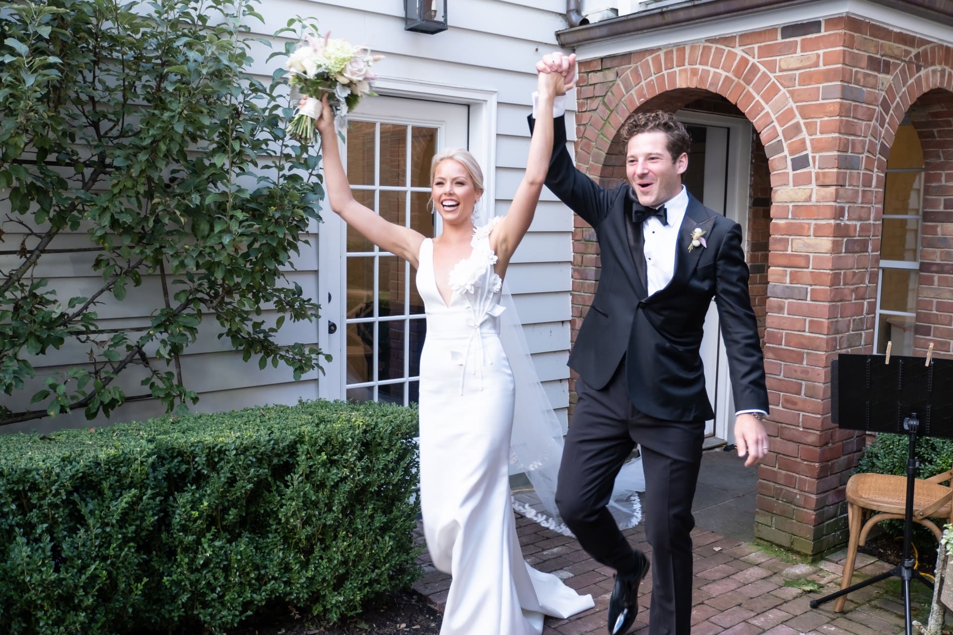 Bride and groom celebrating with raised arms outside the wedding venue
