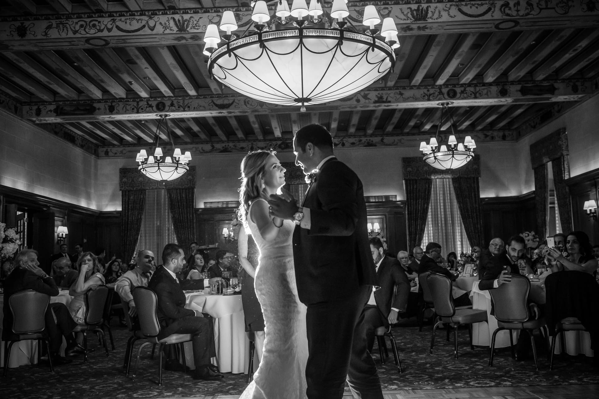 Bride and groom sharing a wedding moment inside an elegant venue with guests watching