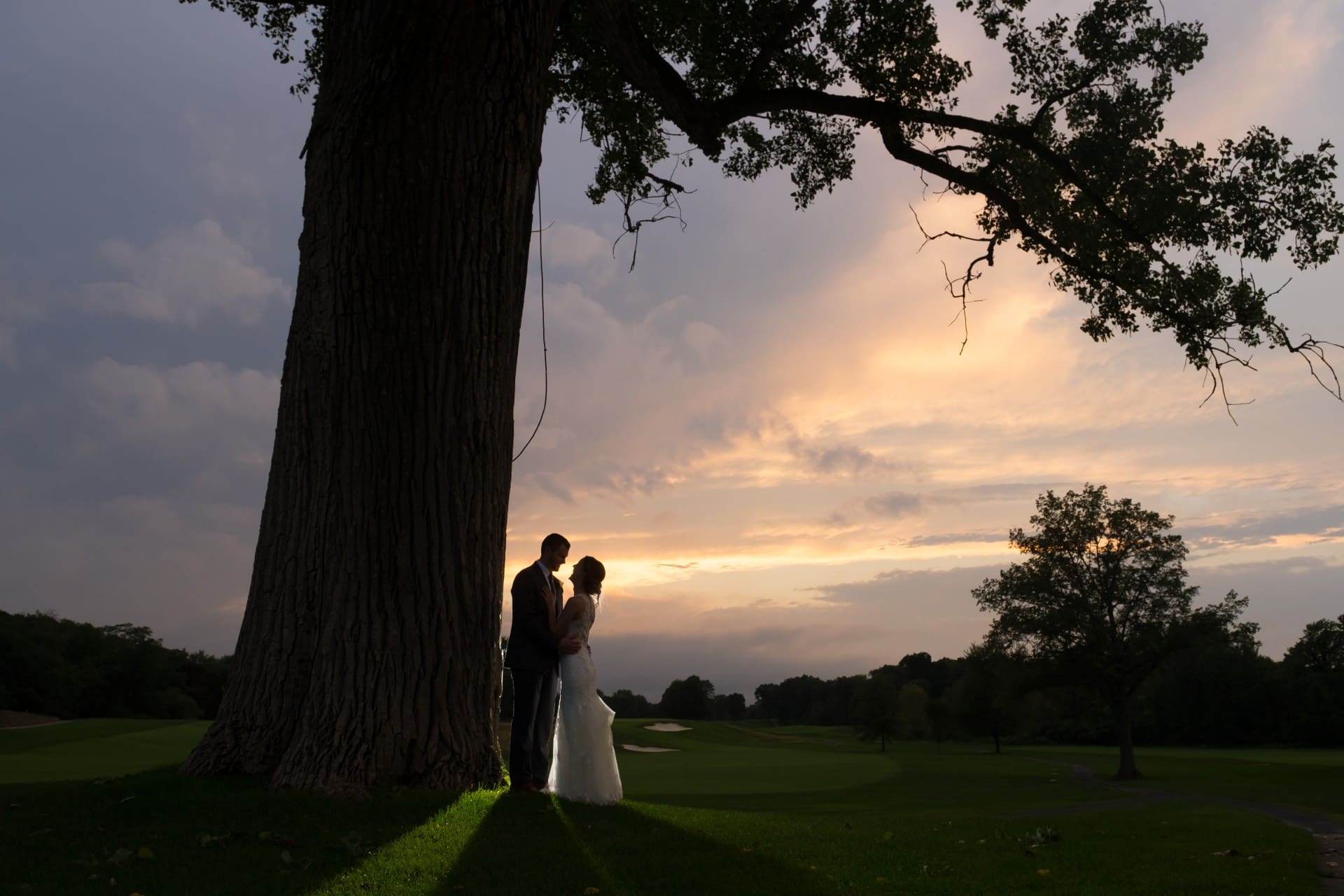 Wedding couple standing together at sunset on the grounds of an Orchard Lake wedding venue in Michigan