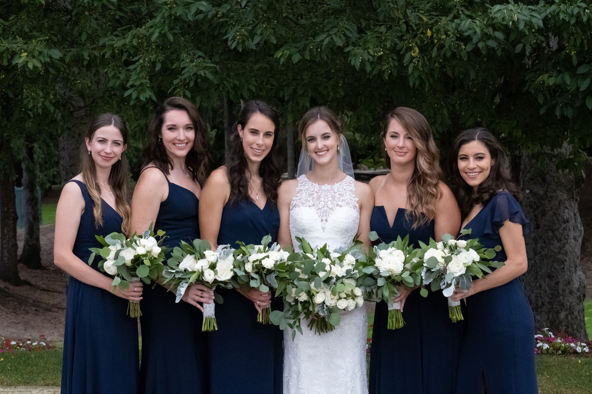 Orchard Lake wedding bride posing with bridesmaids holding white and greenery bouquets